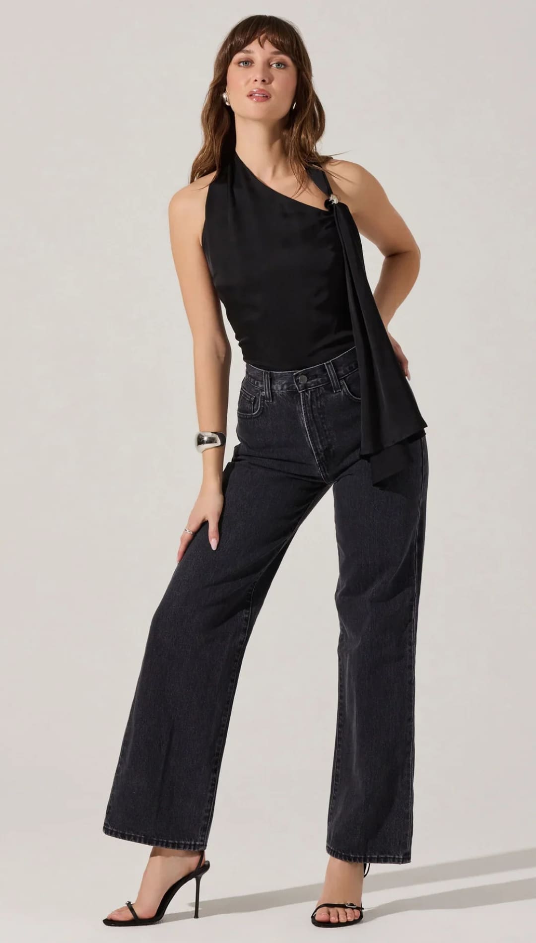 Woman modeling a black halter-neck top and dark wash wide-leg jeans.