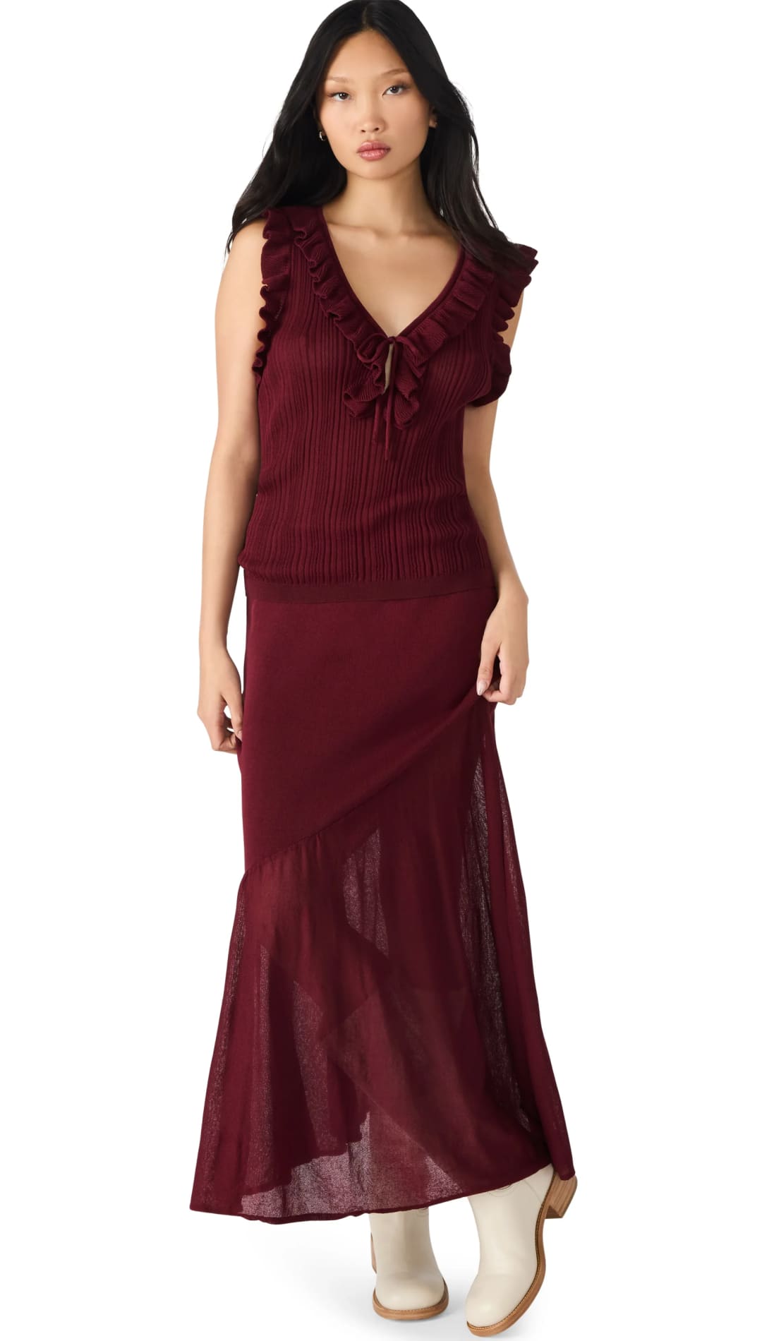 A women’s dark red sleeveless top with ruffled straps and a matching long skirt with a sheer, flared hem, worn with cream-colored ankle boots.