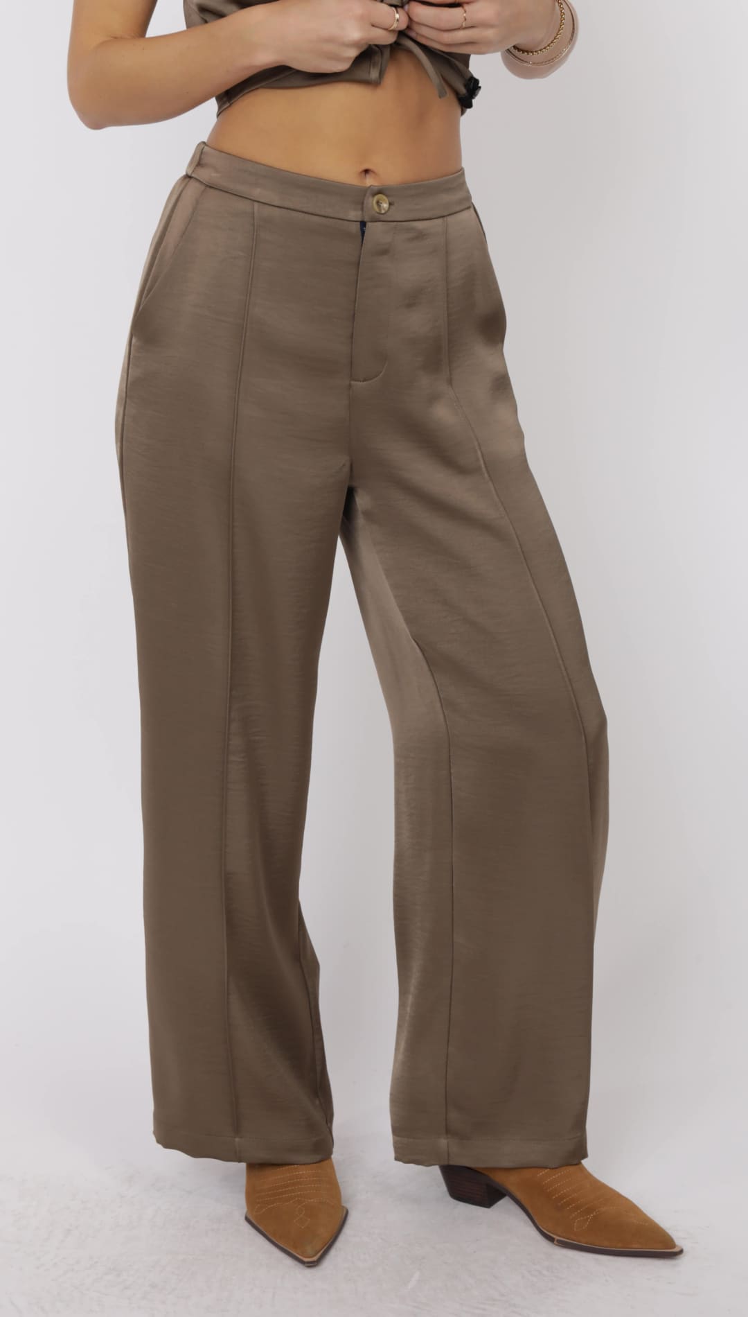 Women’s high-waisted, wide-leg, silky brown trousers with a front button closure.