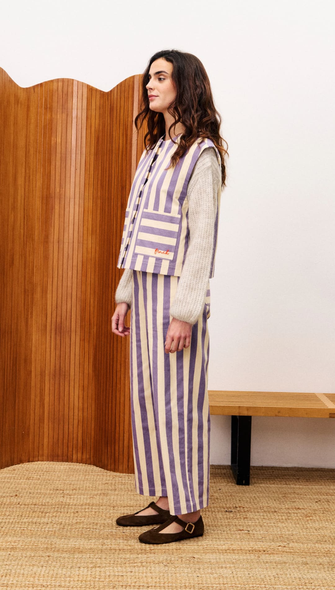 A woman wearing a striped vest, sweater, and pants.