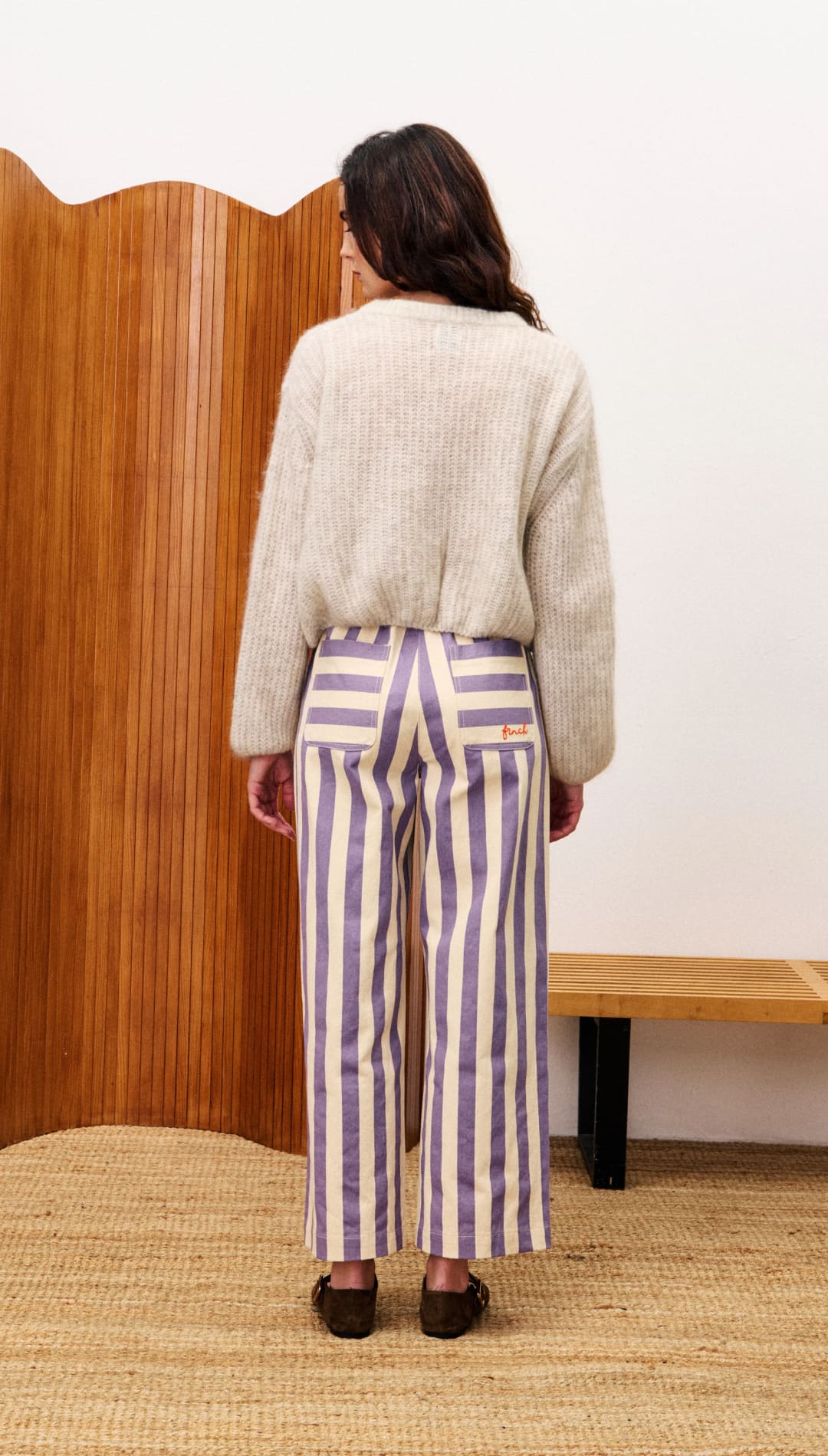 Woman’s beige cropped fluffy sweater with purple and cream striped wide-leg pants.