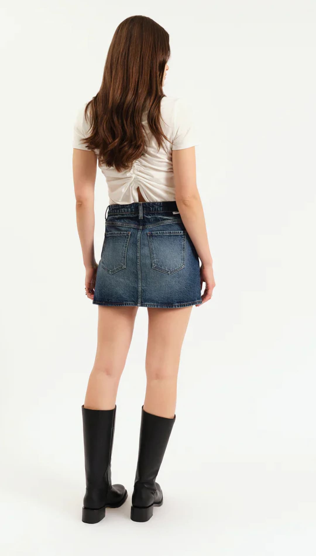 Woman wearing a short-sleeved top, denim mini-skirt, and knee-high boots.
