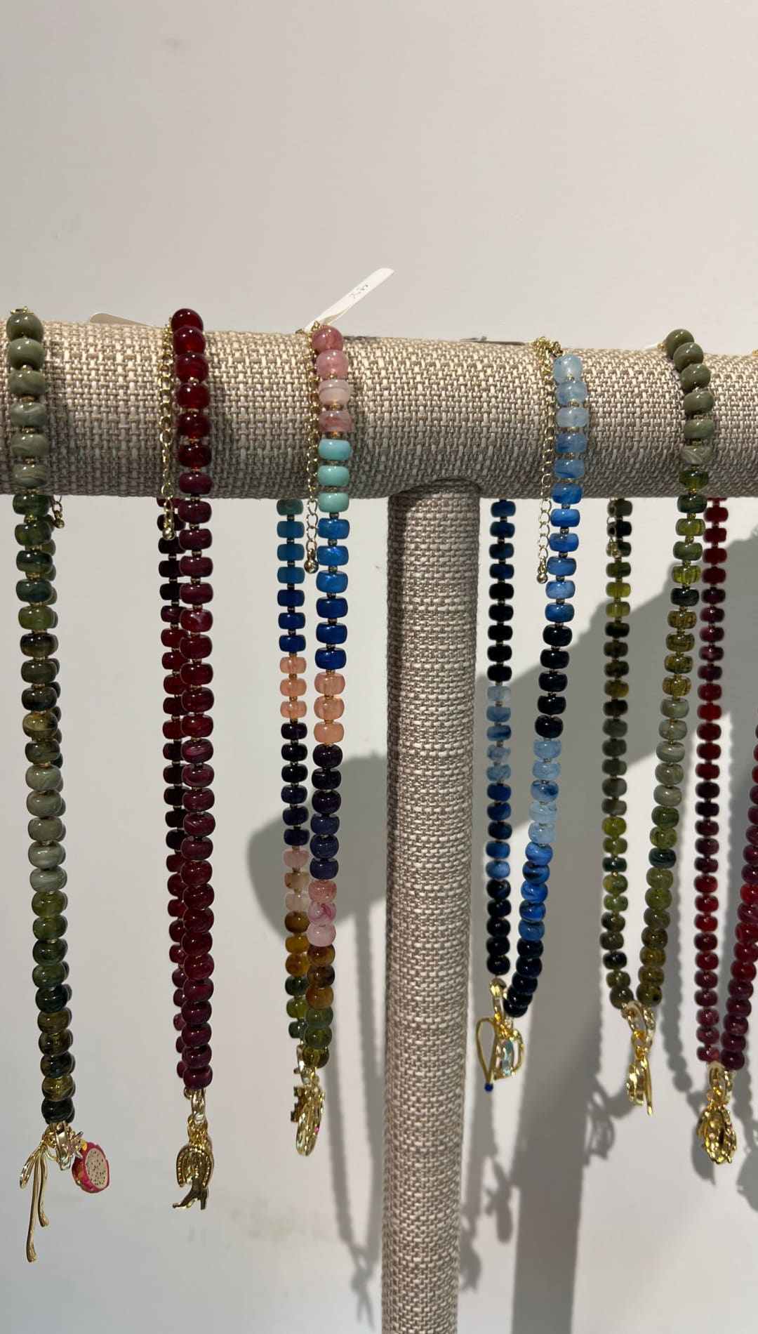 Multiple colorful beaded necklaces with gold charms.