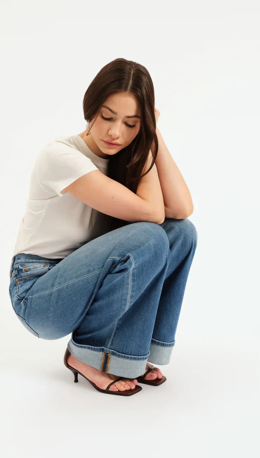 Blue denim jeans with rolled cuffs and brown leather sandals.