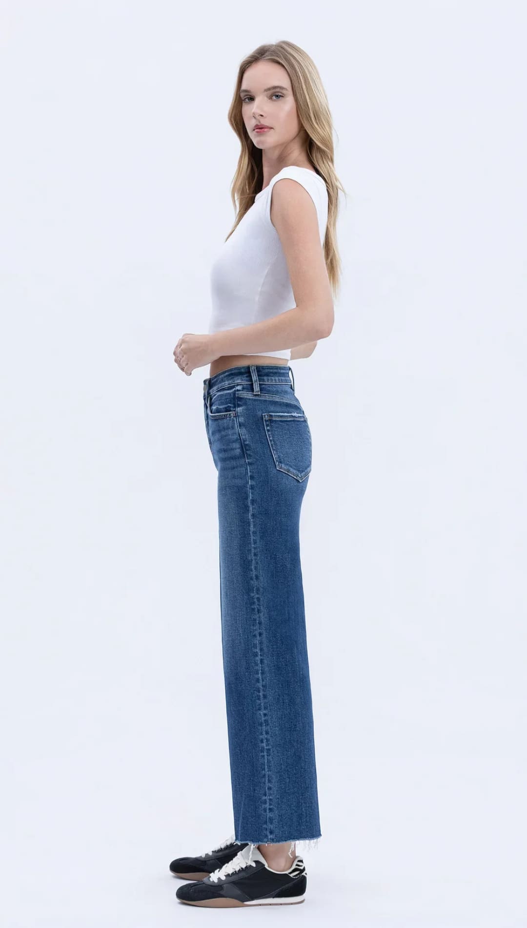 Woman wearing a white cropped t-shirt and wide-leg blue jeans.