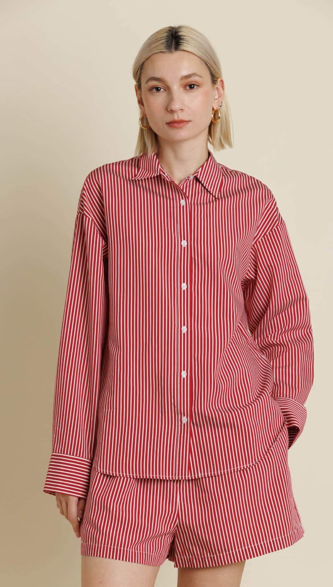 A red and white striped pajama set with a long-sleeve button-up shirt and shorts.