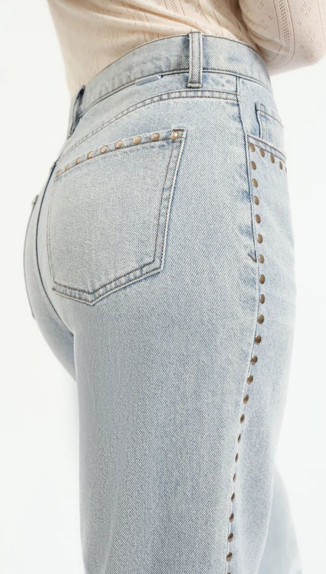 Light-wash denim jeans with studded side seams.