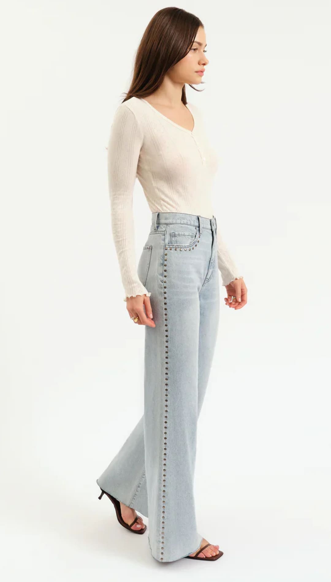 Woman wearing light-wash studded jeans.