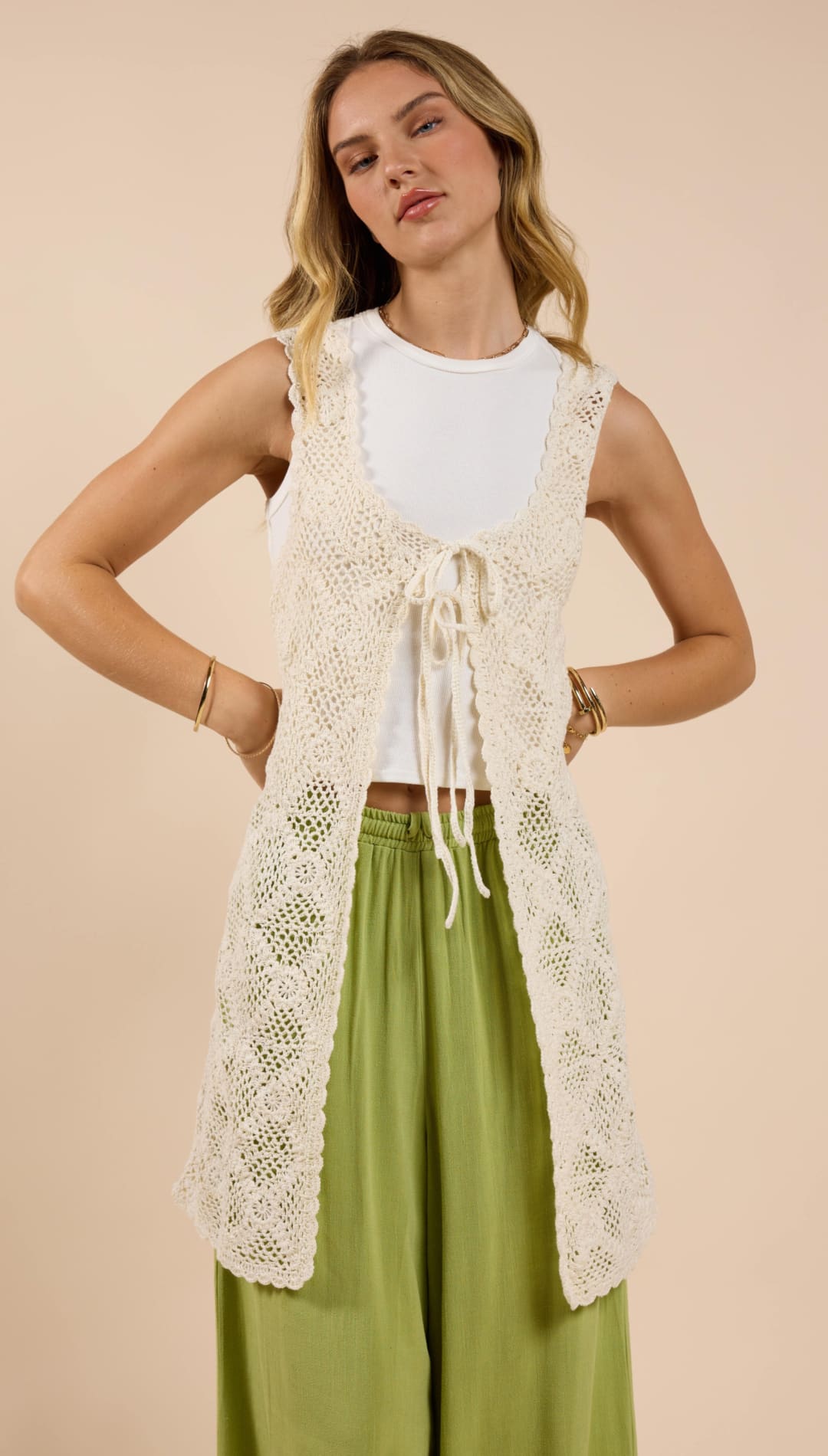 Woman’s long, cream-colored, crocheted vest.