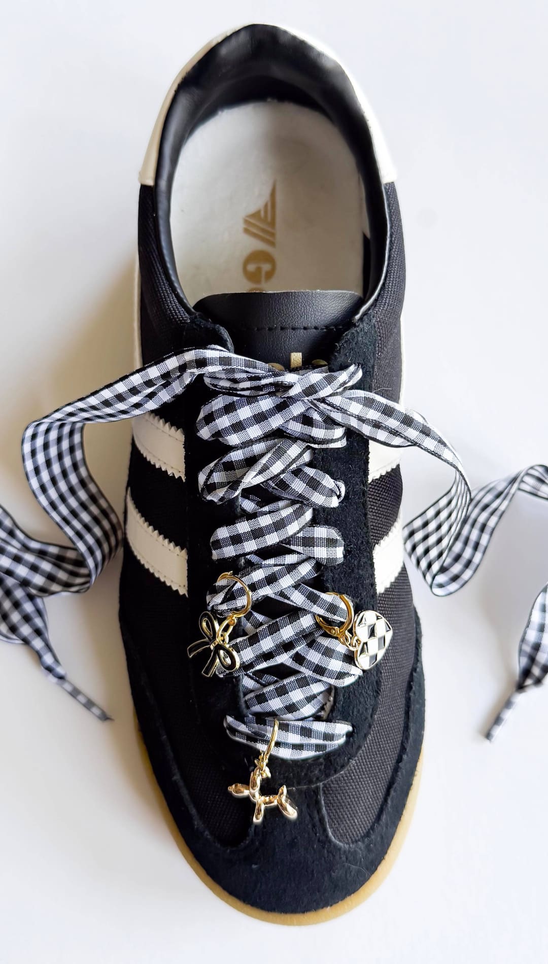 Black sneaker with gingham ribbon laces and charms.