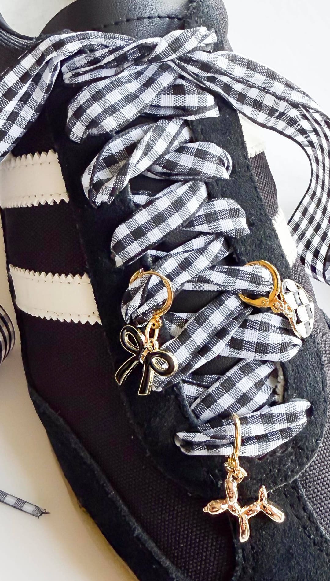 Black sneaker with gingham ribbon laces and charms.