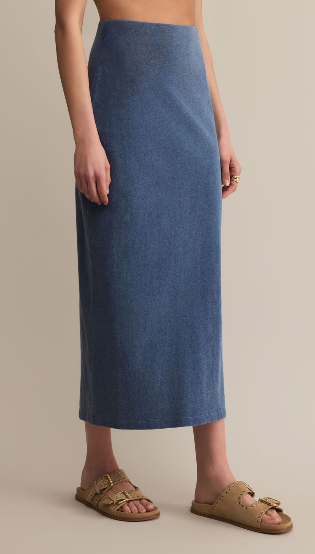 A long, blue denim-look skirt paired with light brown, double-buckle slide sandals.
