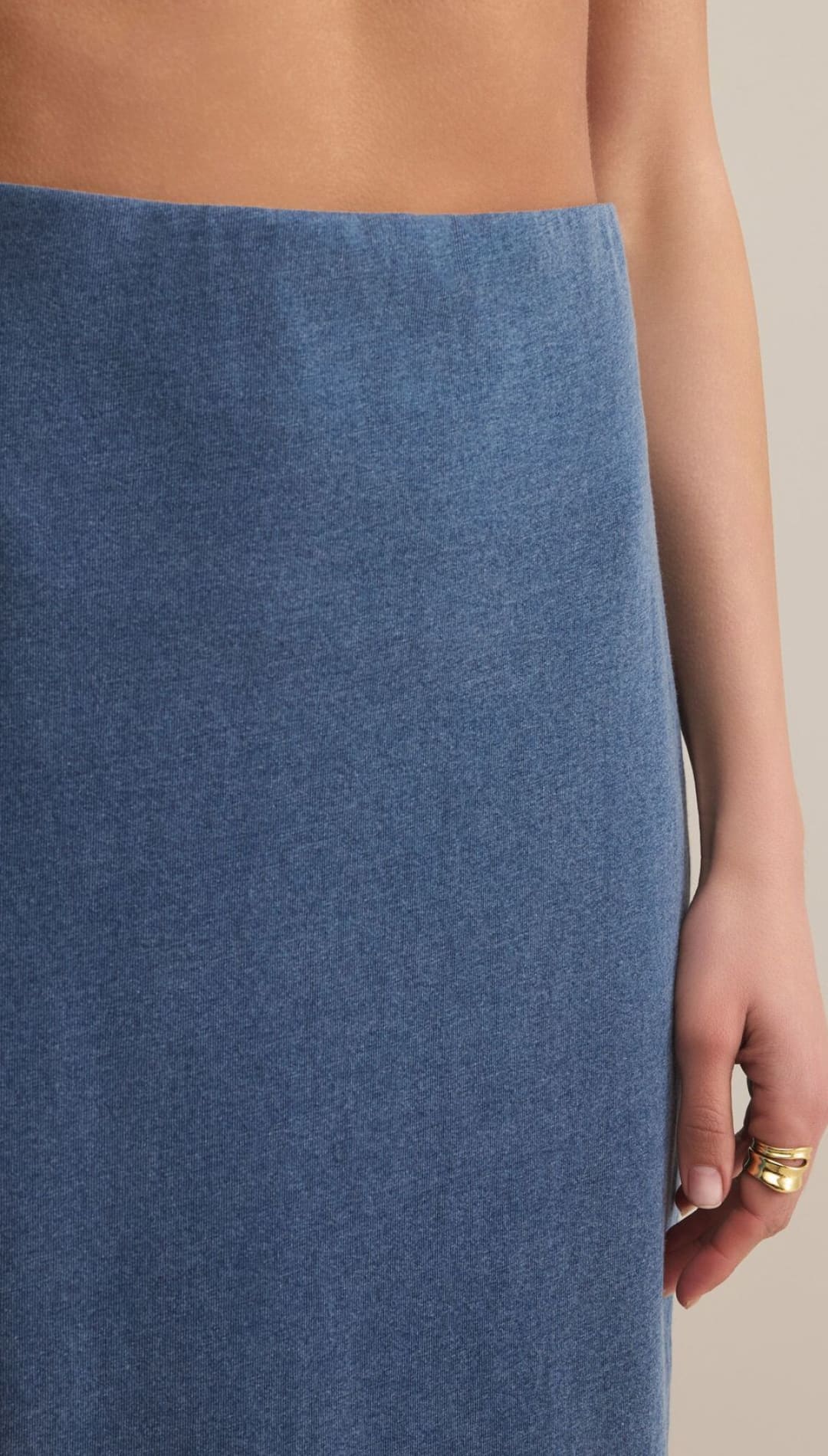 A person wearing a blue denim midi skirt with a clean, unadorned waistband.