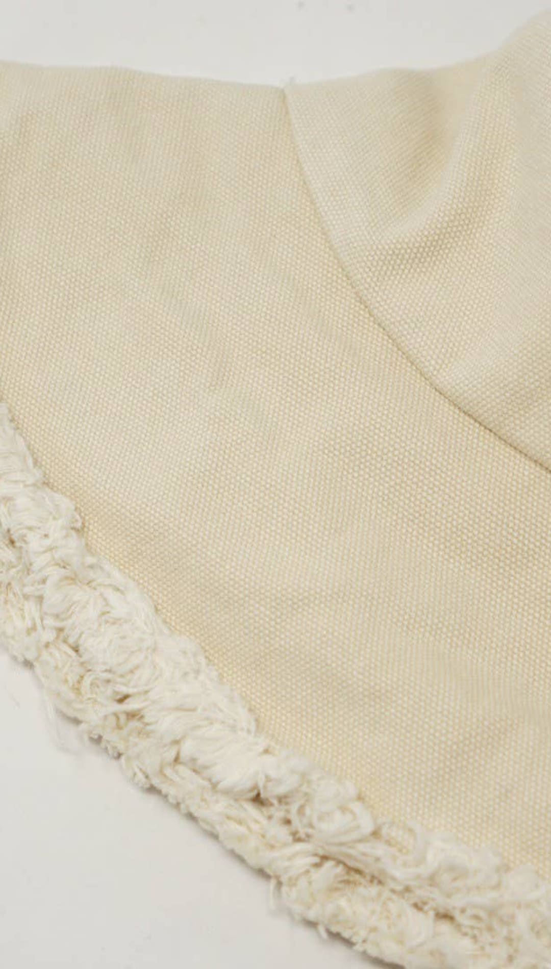 Beige bucket hat with fringed brim.