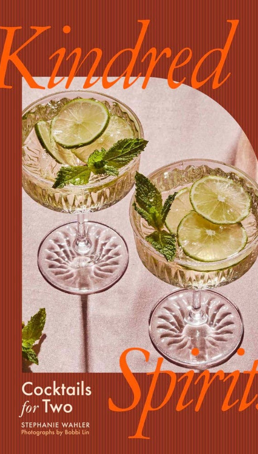 Classic crystal cocktail glasses with lime slices and mint leaves, set against a warm brown background.