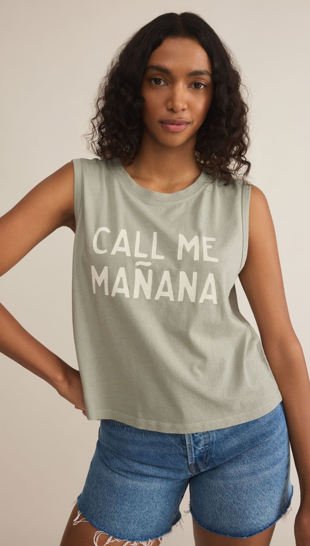 Woman wearing a sleeveless shirt and denim shorts.