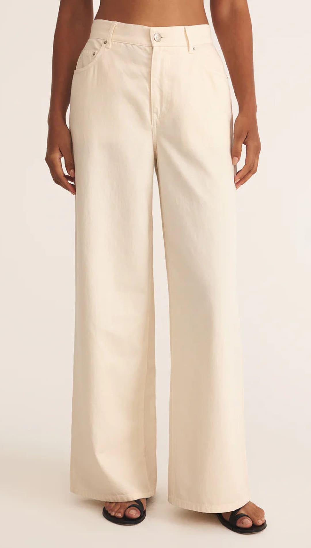 Cream-colored wide-leg pants with button details and pockets.