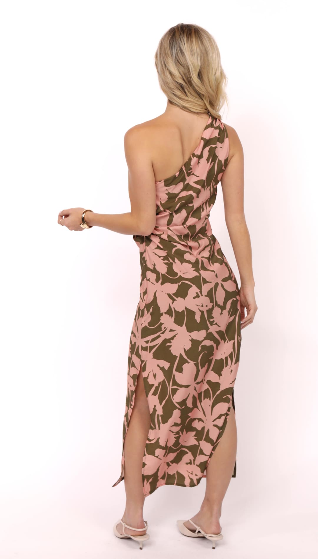 One-shoulder maxi dress with a pink and olive green tropical leaf print and side slits.
