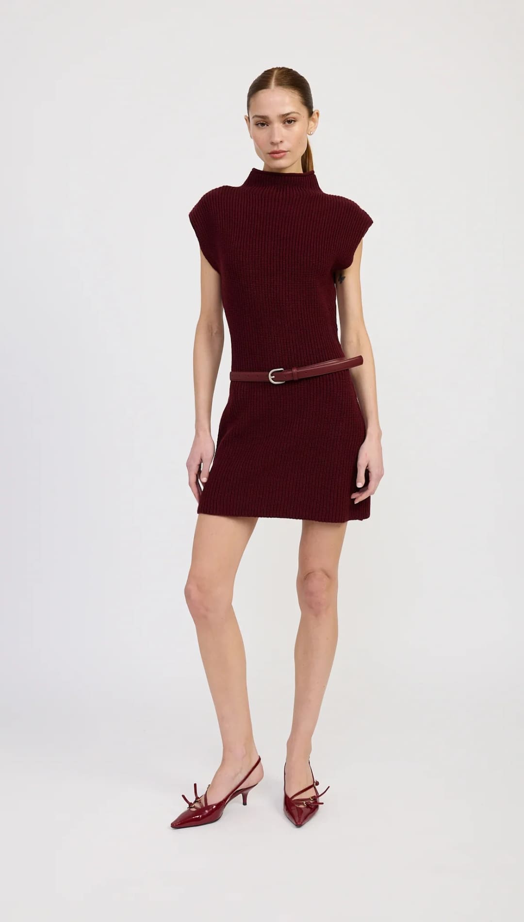 A short-sleeved, mock-neck maroon knit mini dress with a thin matching belt.