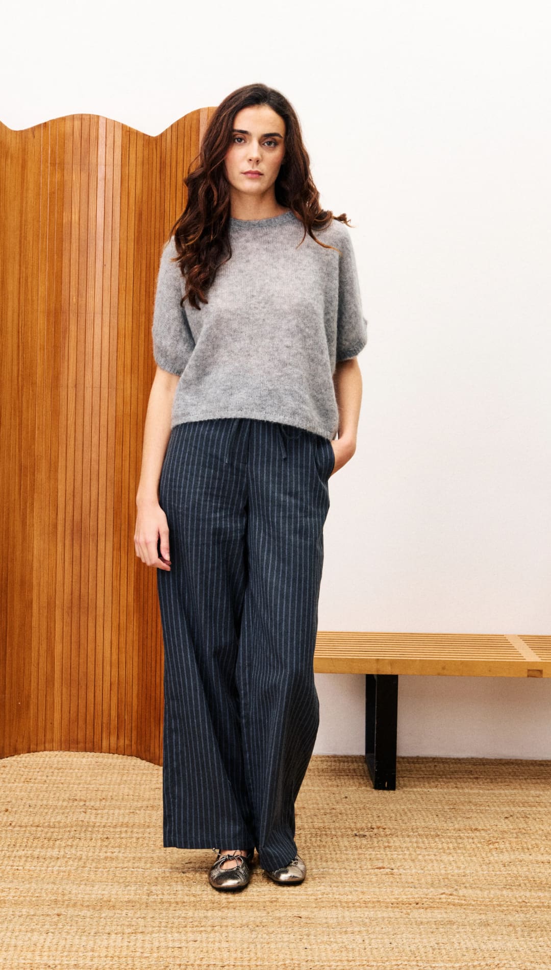 Women’s grey short-sleeved sweater with dark pinstriped wide-leg pants.