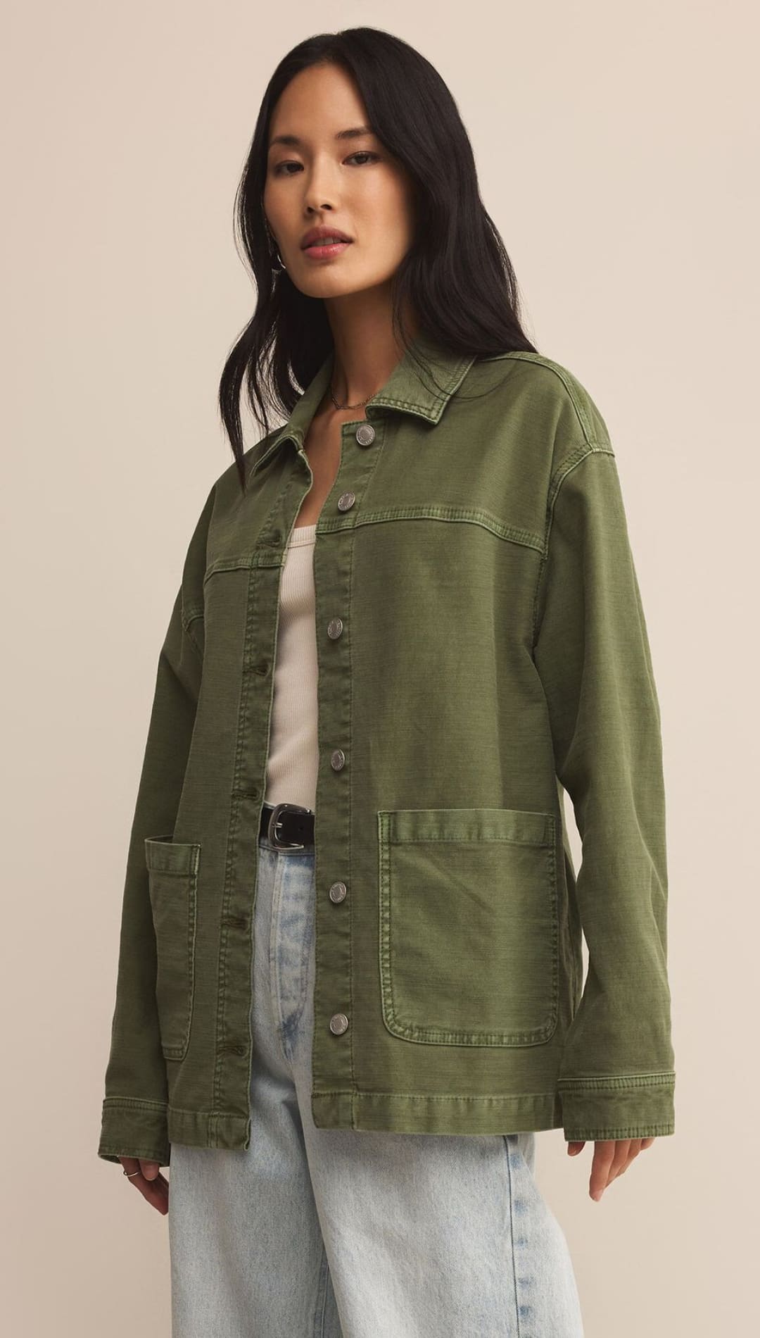 Woman wearing an olive green utility jacket and light wash jeans.