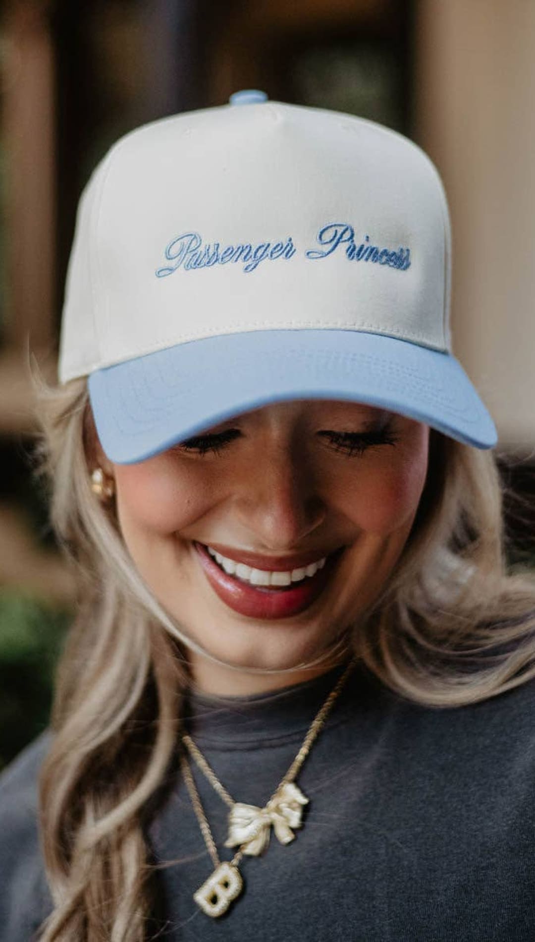 White and light blue ’passenger princess’ baseball cap with embroidered text, cotton material.
