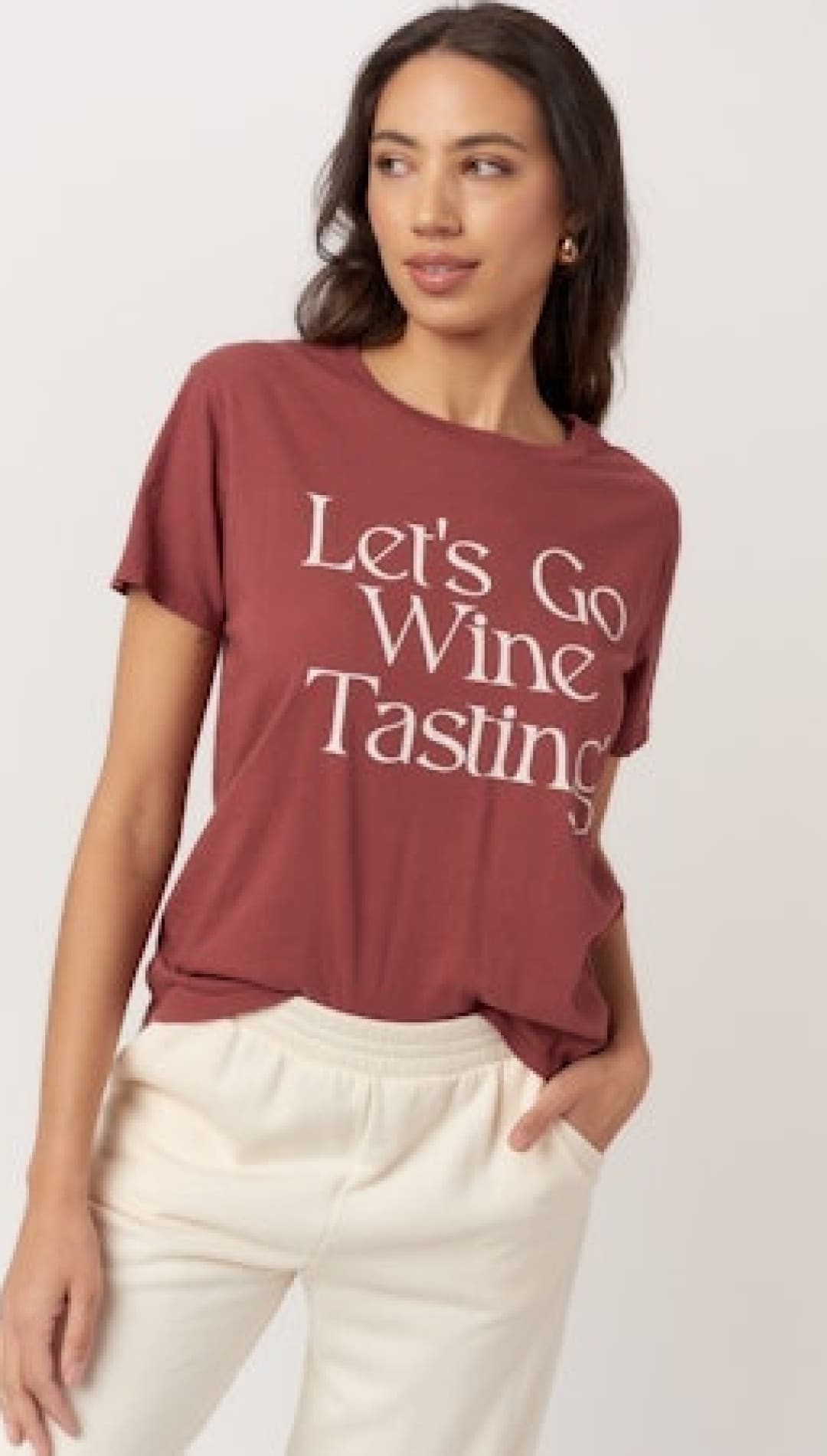 A woman’s short-sleeved t-shirt in a reddish-brown color with the text ’Let’s Go Wine Tasting’ printed on the front.