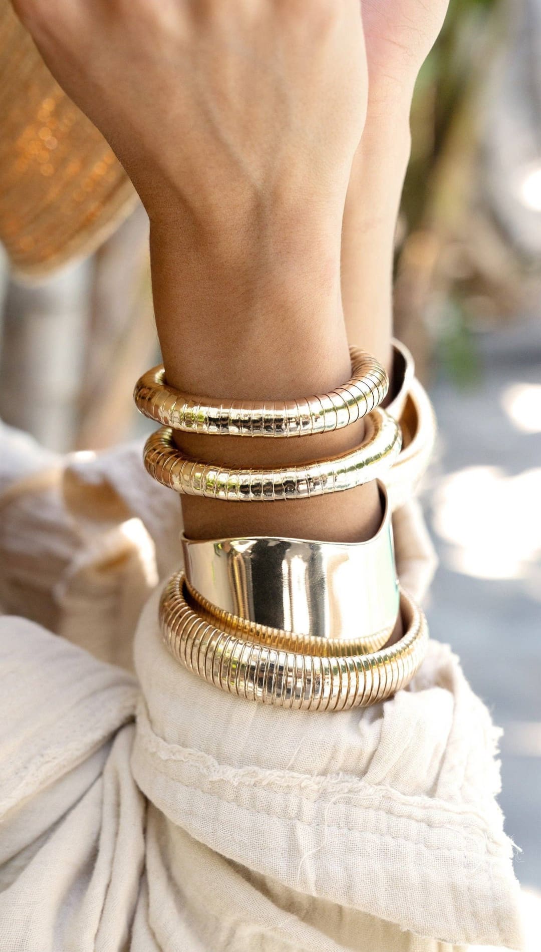 Gold-toned bracelets on a wrist.