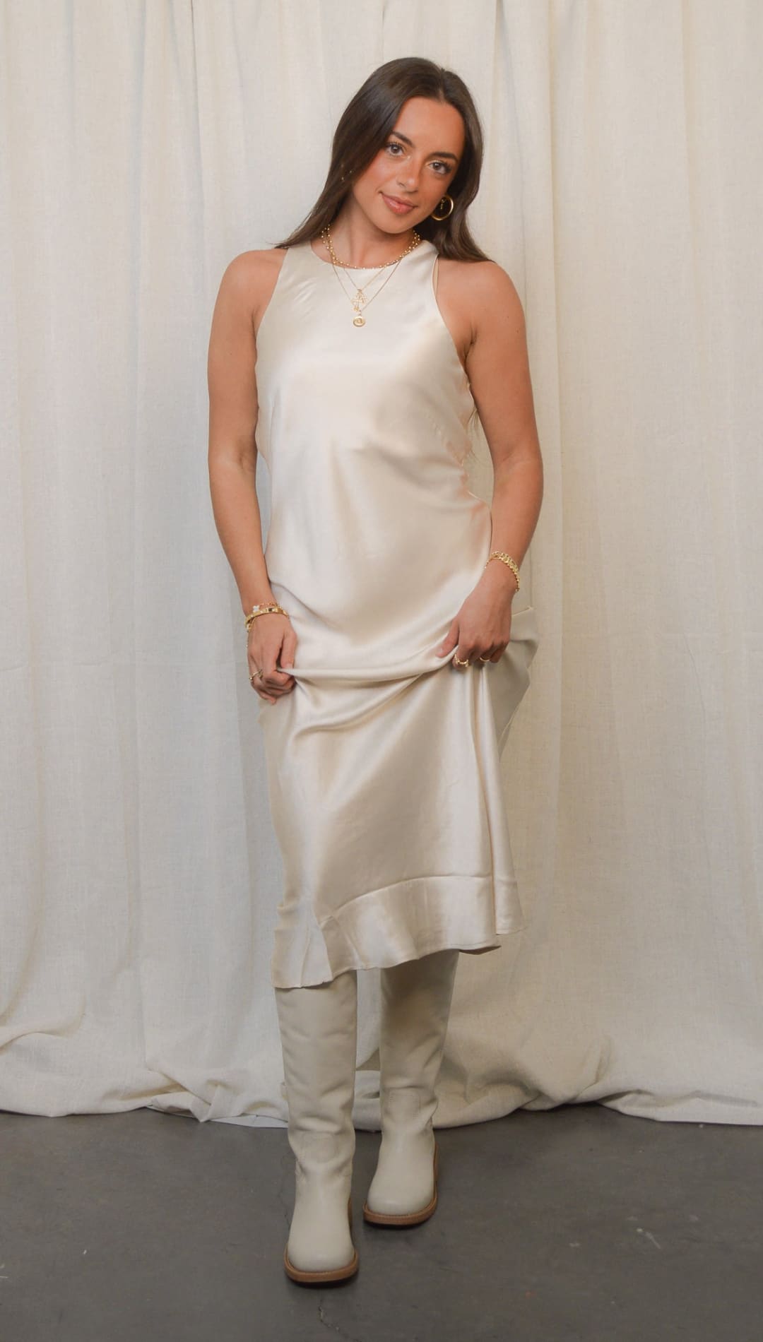 Sleeveless satin dress with knee-high boots.