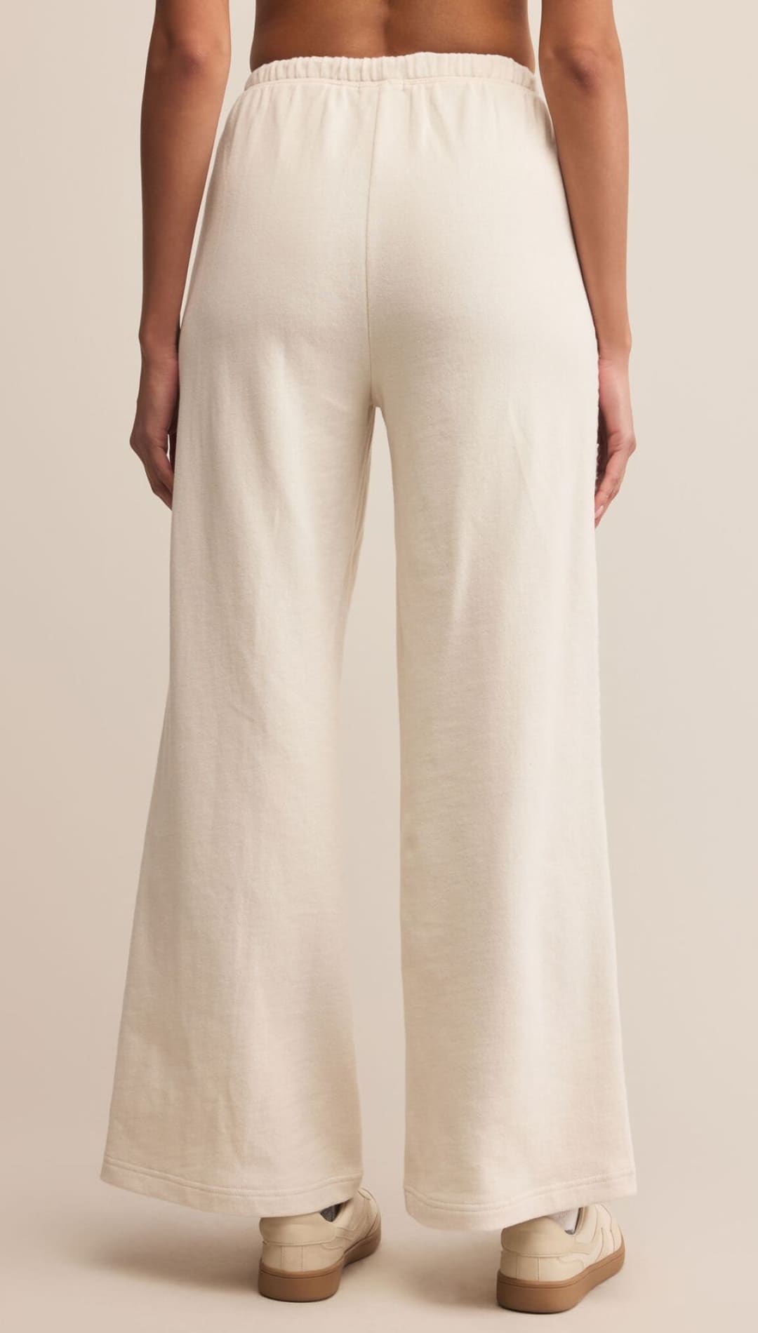Cream-colored wide-leg pants with elastic waistband and side stripe, likely from a casual wear brand.