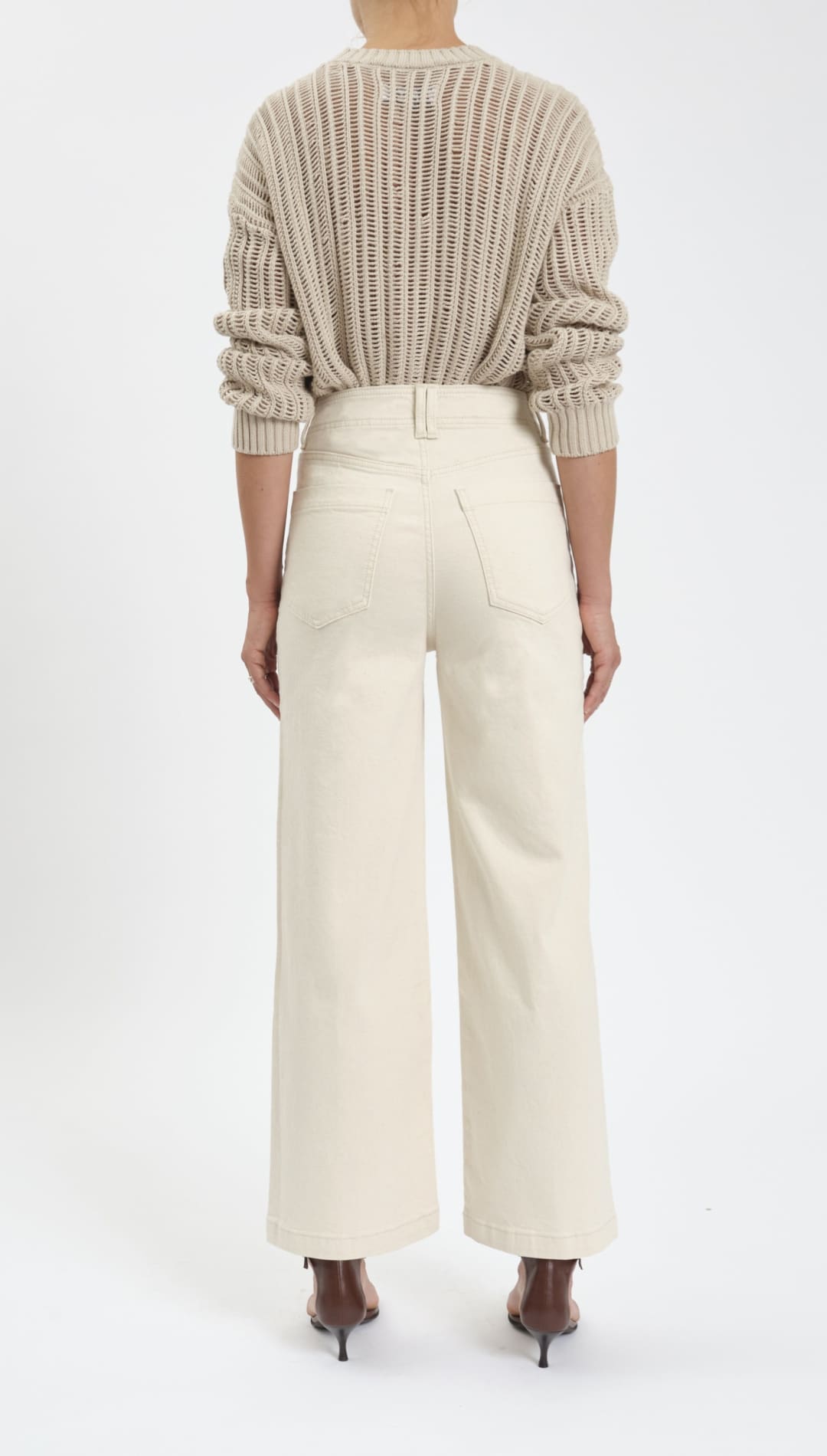Woman wearing a beige sweater and wide-leg cream pants.