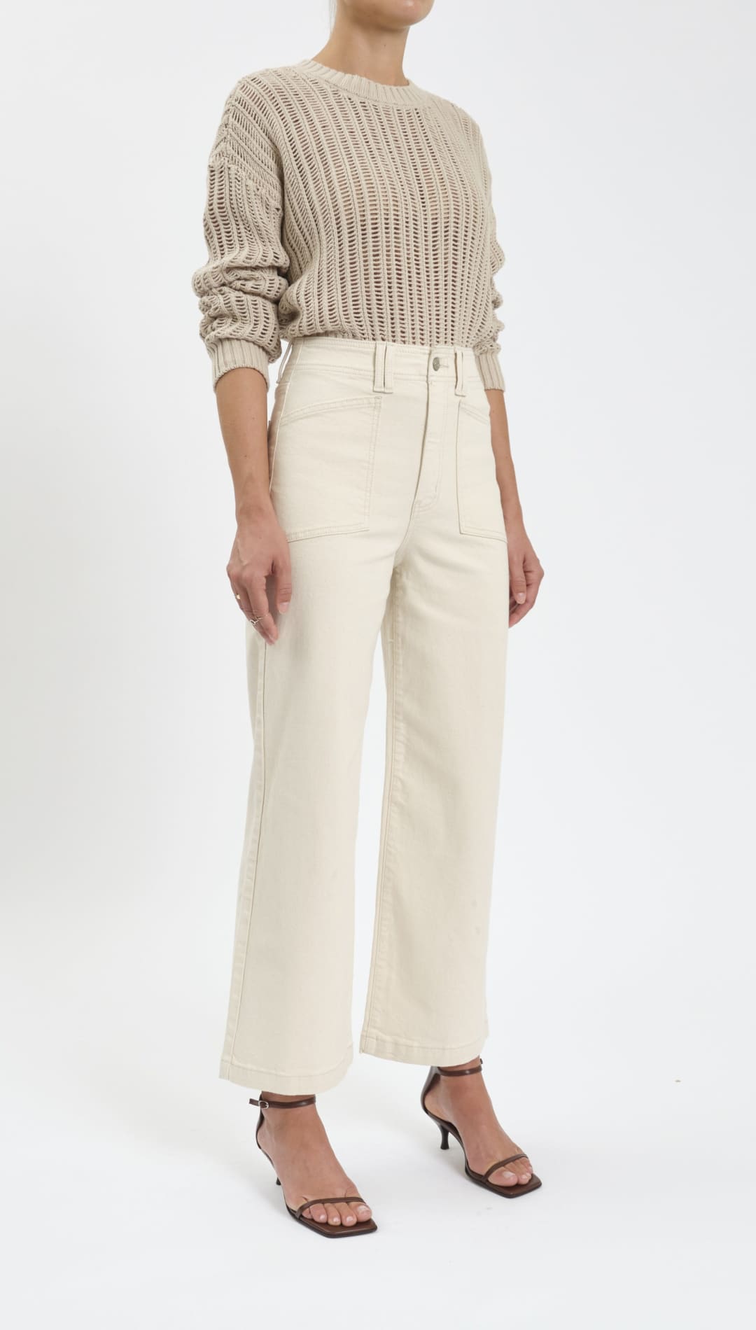 Woman wearing a beige sweater and white pants.