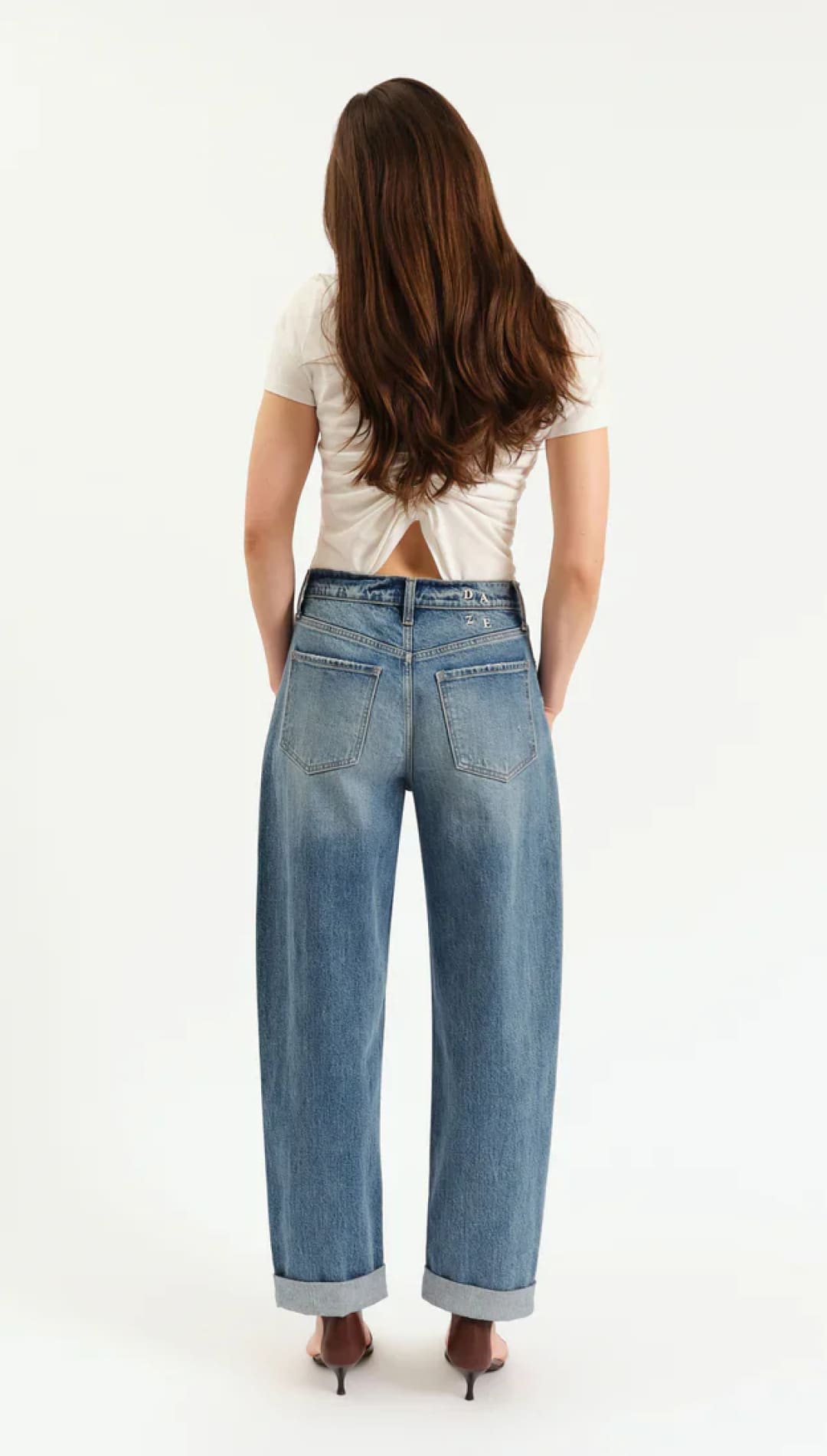 Woman’s light wash, wide-leg jeans with cuffed hems and a white twisted-back crop top.