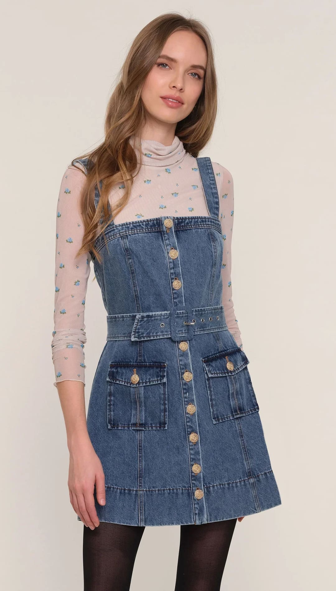 A denim pinafore dress with a full button front, a belted waist, and large patch pockets.