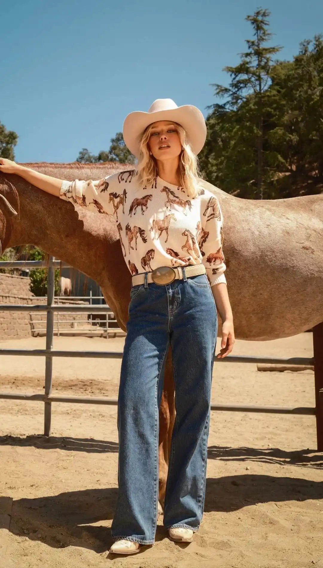 Western-style women’s outfit with a horse-print top, wide-leg jeans, and a cowboy hat.