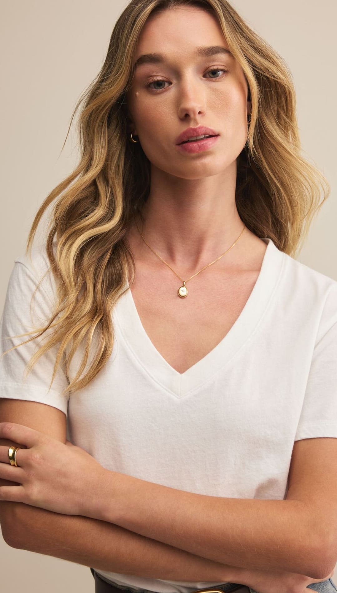 A woman wearing a white V-neck t-shirt and a gold necklace.