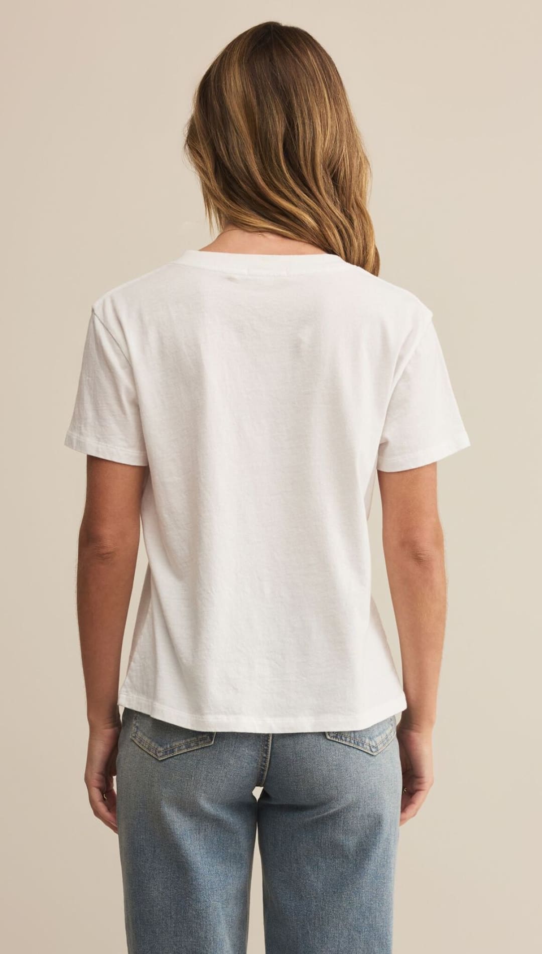 A woman’s plain white short-sleeved t-shirt made of cotton or a similar soft fabric, paired with light-wash blue jeans.