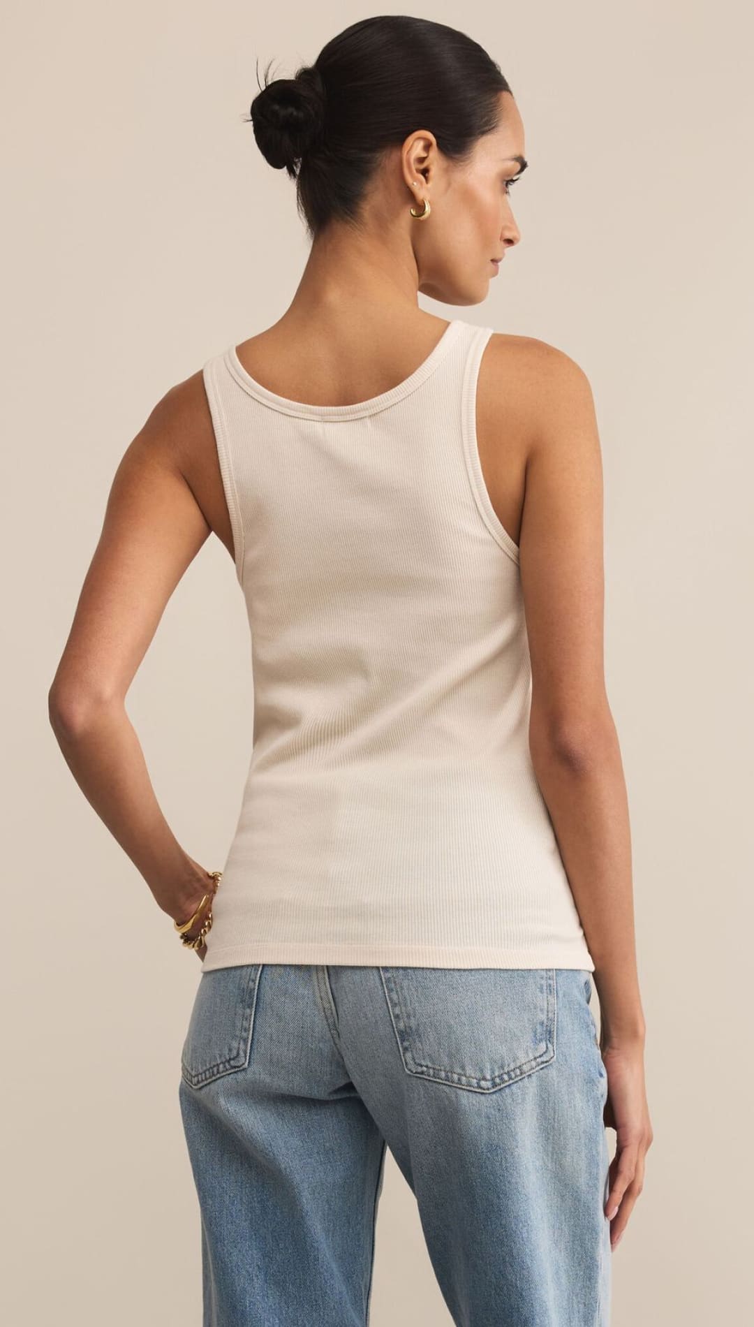 Cream ribbed tank top and light wash wide-leg jeans.