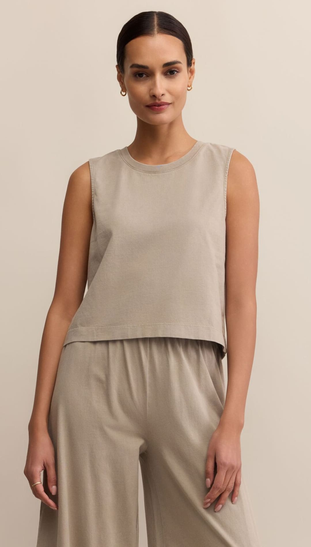 A woman modeling a sleeveless, crew-neck beige top and matching wide-leg pants.