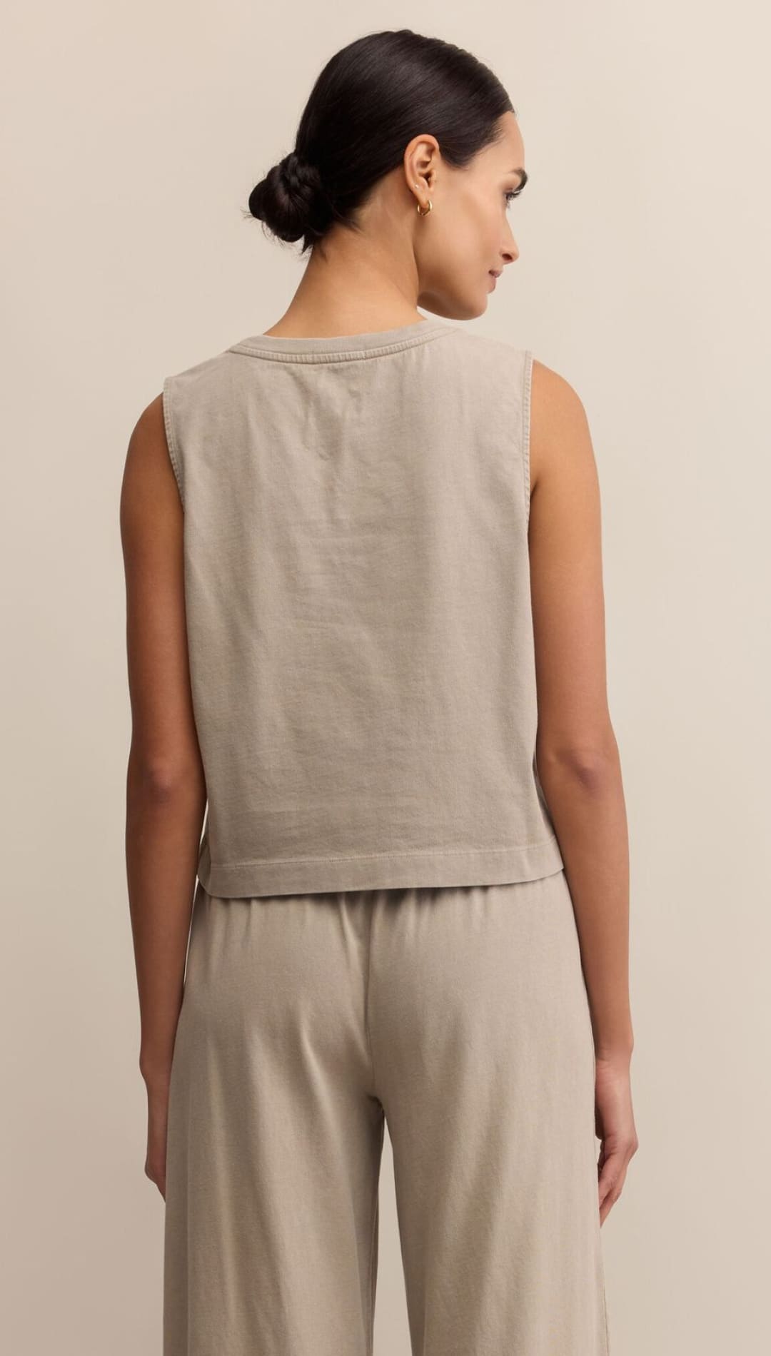 A woman modeling a light brown sleeveless shirt and matching wide-leg pants.