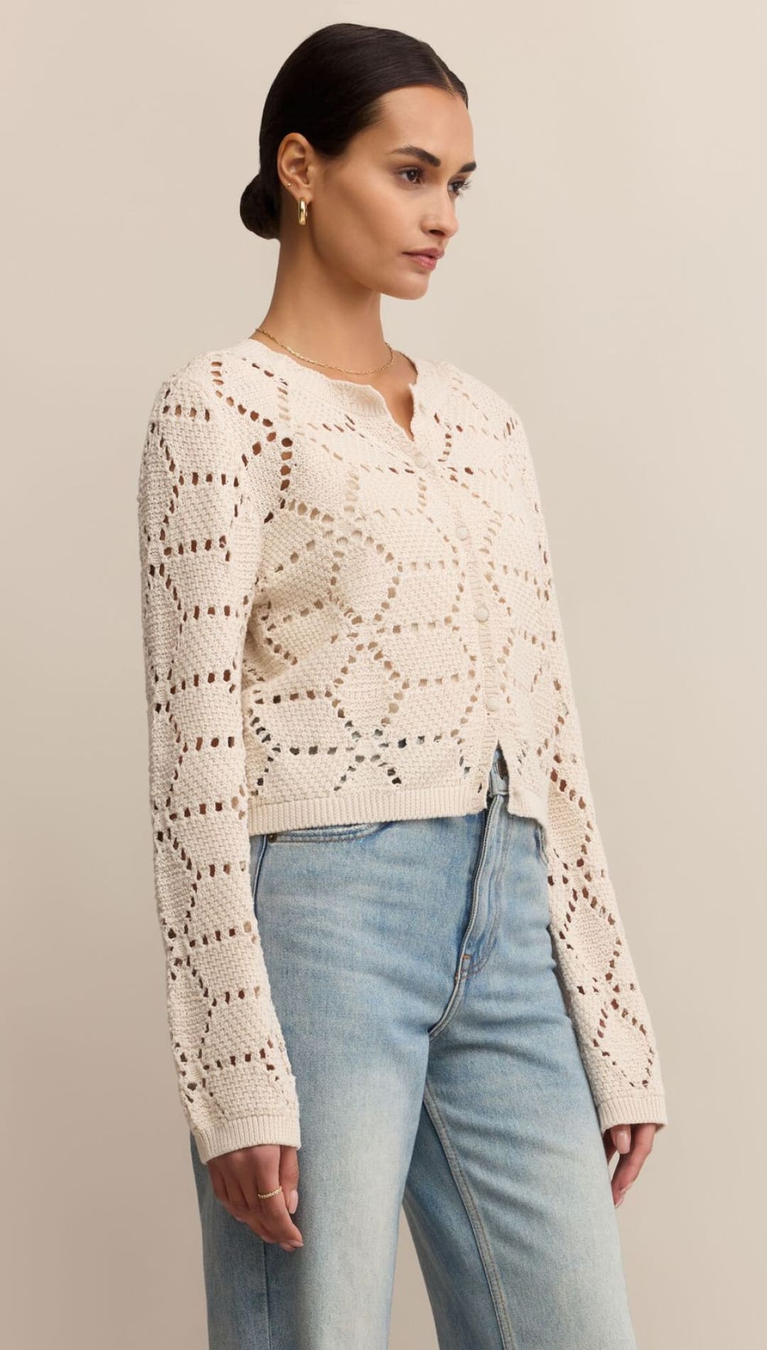 Cream-colored, open-knit cardigan with geometric patterns and a V-neckline.
