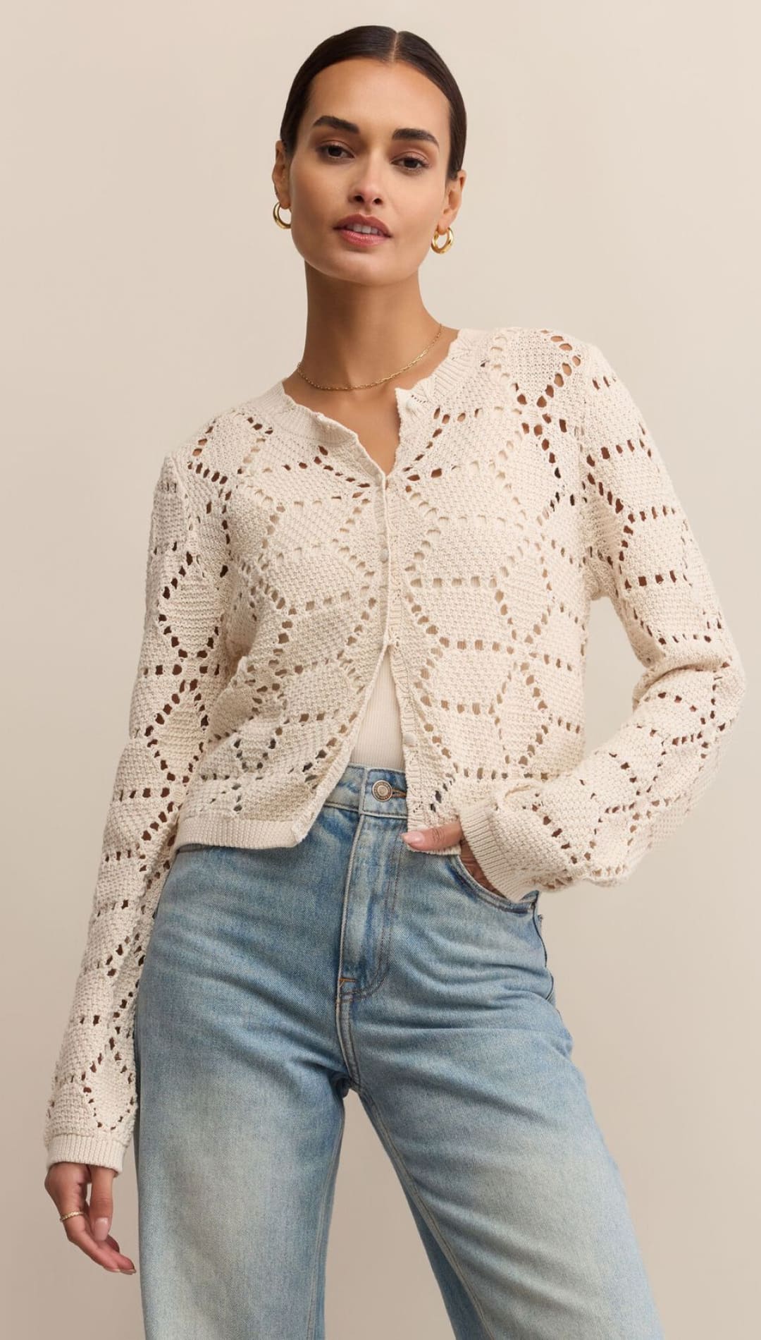 Cream-colored open-knit cardigan with geometric patterns and long sleeves.