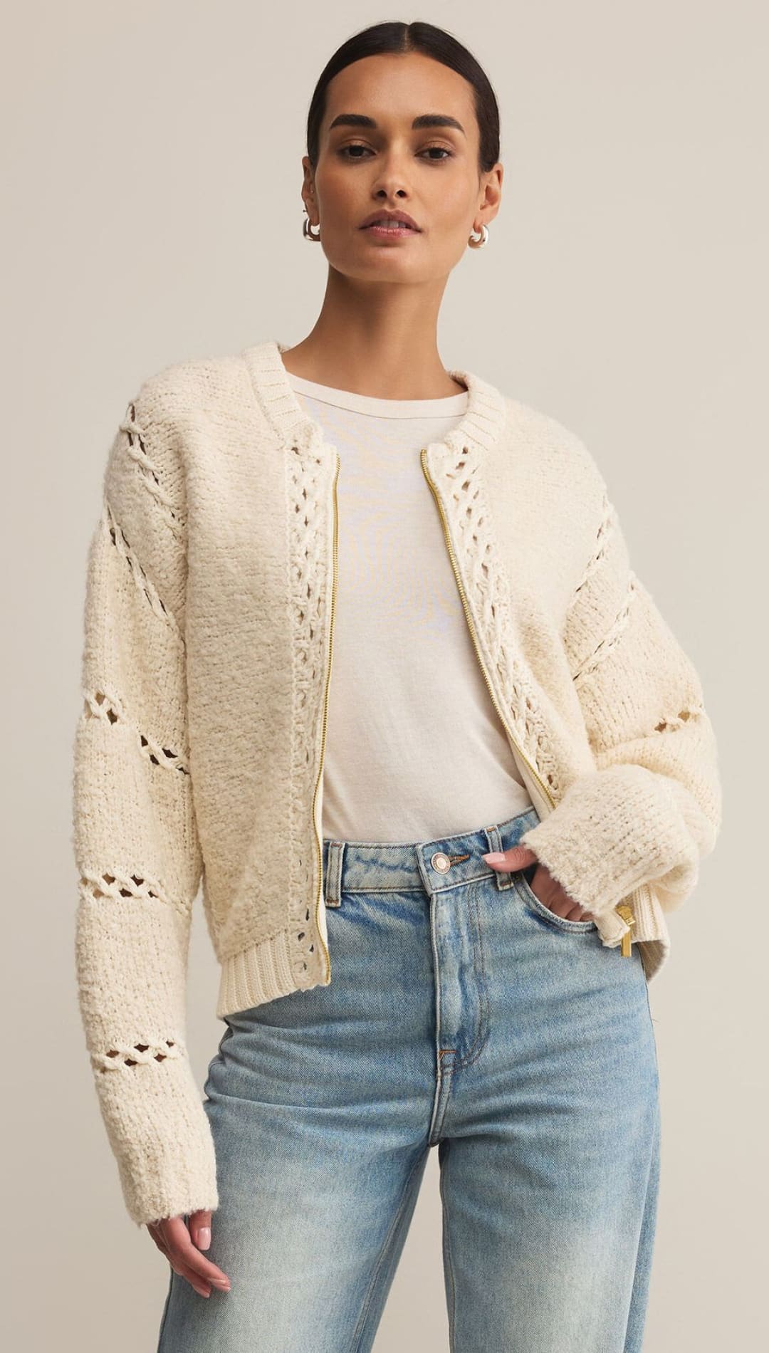 Cream-colored, open-knit zip-up cardigan with long sleeves and a ribbed hem.