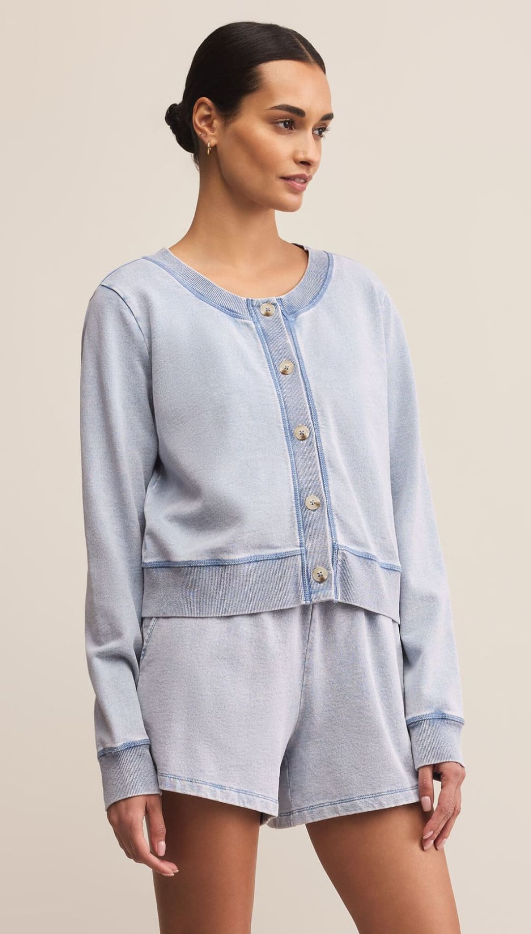 A woman wearing a light blue button-up cardigan and matching shorts.