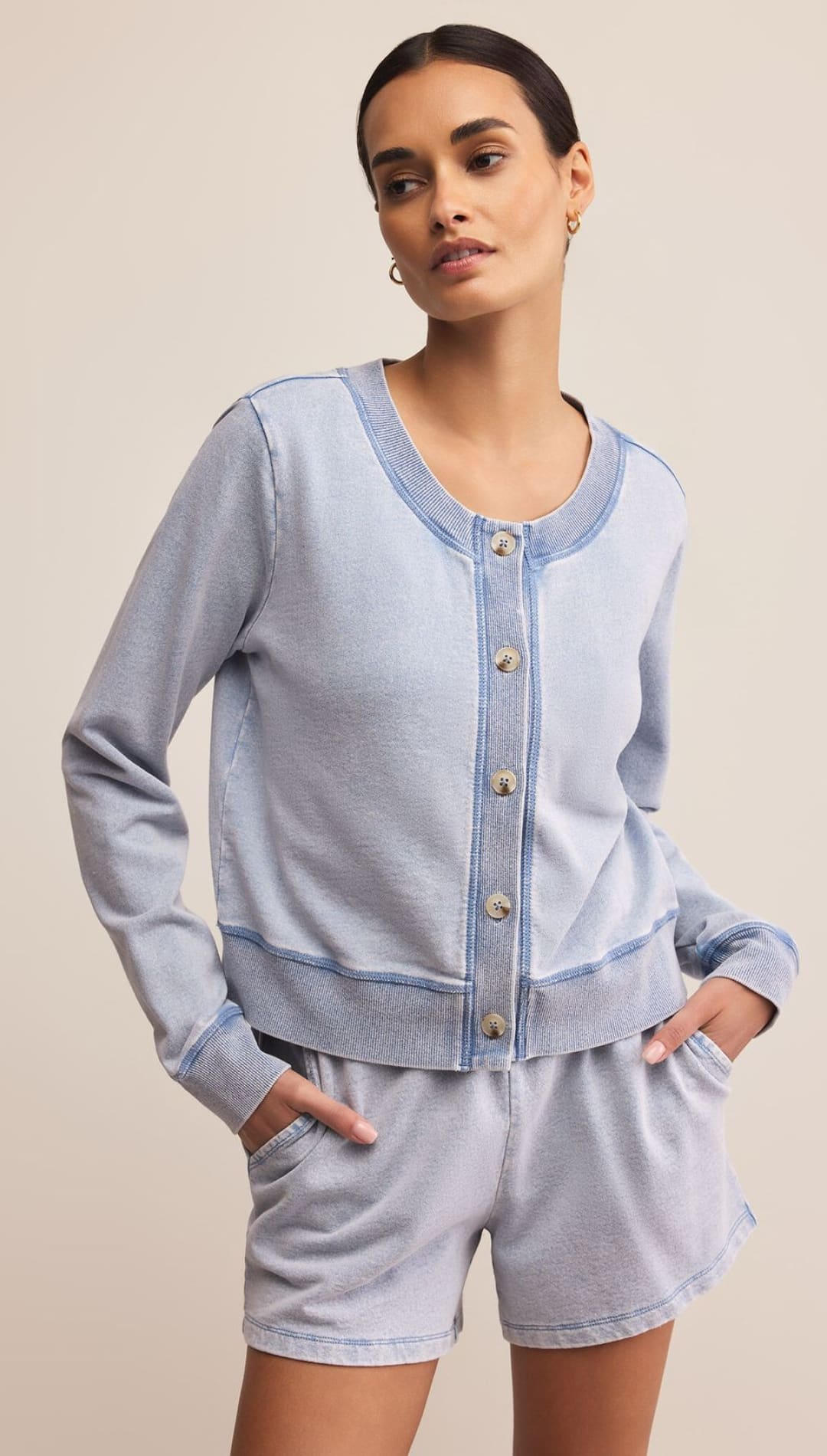 A woman models a light blue button-up cardigan and matching shorts.