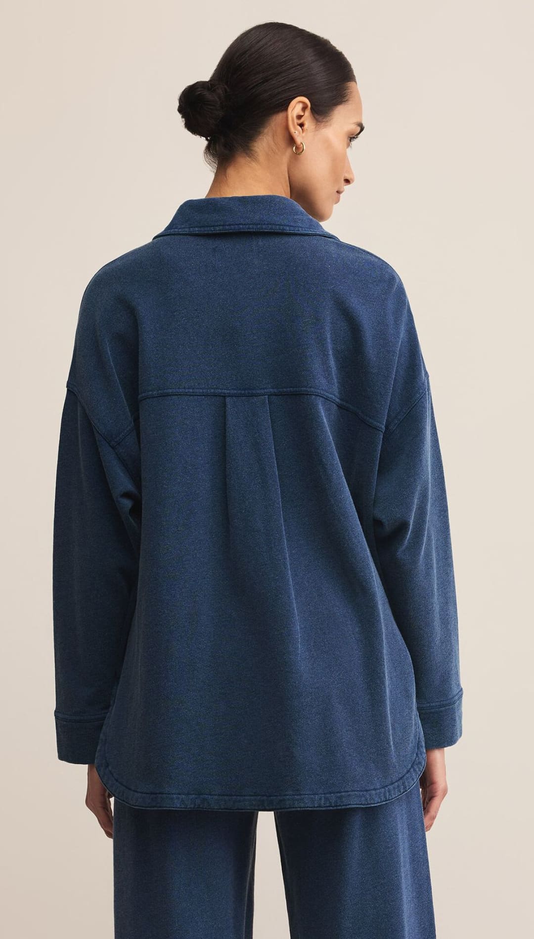 A woman in a relaxed-fit, long-sleeved dark blue shirt and matching wide-leg pants.