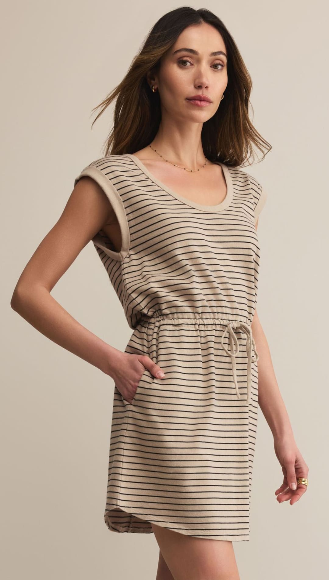 A beige and black striped sleeveless mini dress with a drawstring waist and pockets.